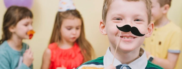 Boy wearing a paper moustache at a birthday party